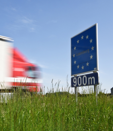 Camion roulant à vive allure devant un panneau européen au Luxembourg avec de l'herbe devant lui