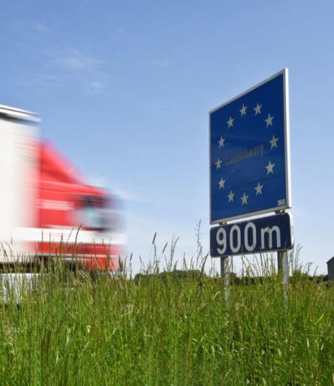 Truck speeding past a European sign in Luxembourg with grass in front of it