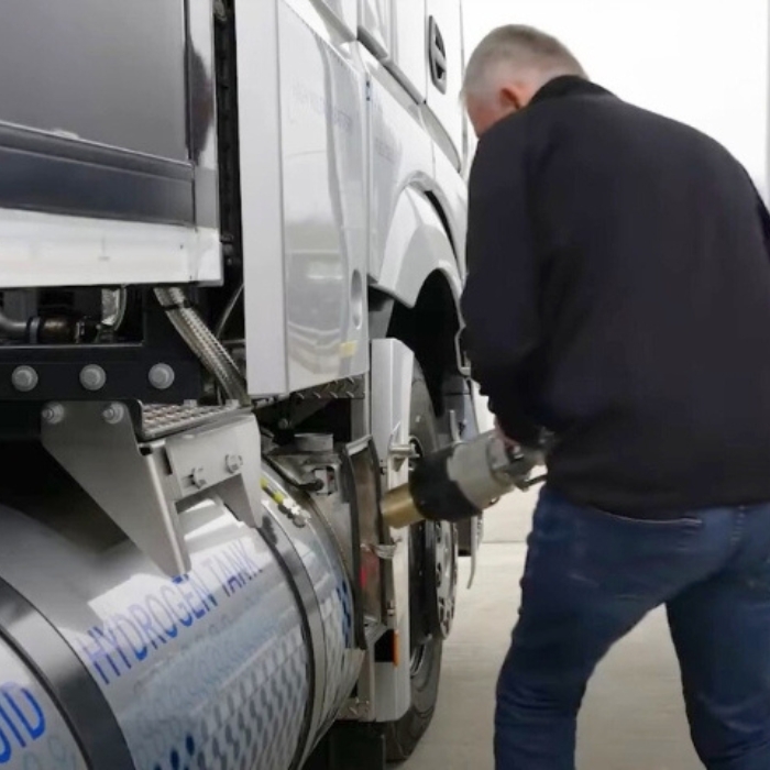 Man refueling a hydrogen-powered truck at a filling station